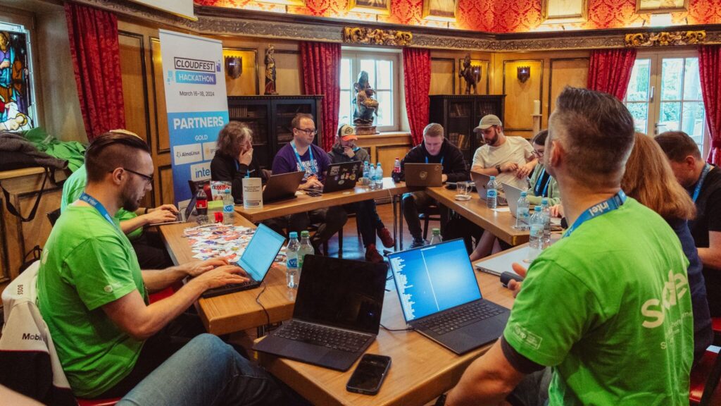 Thorsten Frommen, Christian Leucht and Robert Windisch collaborating at a table with other participants during the Cloudfest Hackathon